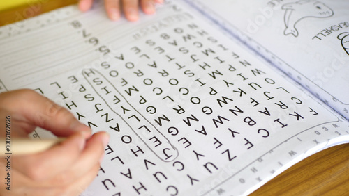 Close up of a kid solving a word search puzzle