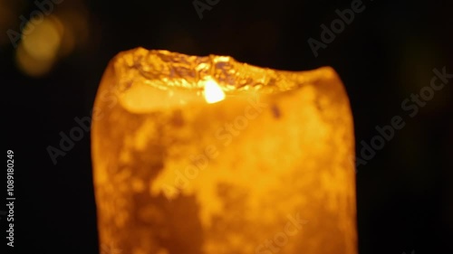 A glowing candle flickering gently on a cozy evening setting in 4K slow motion 60fps