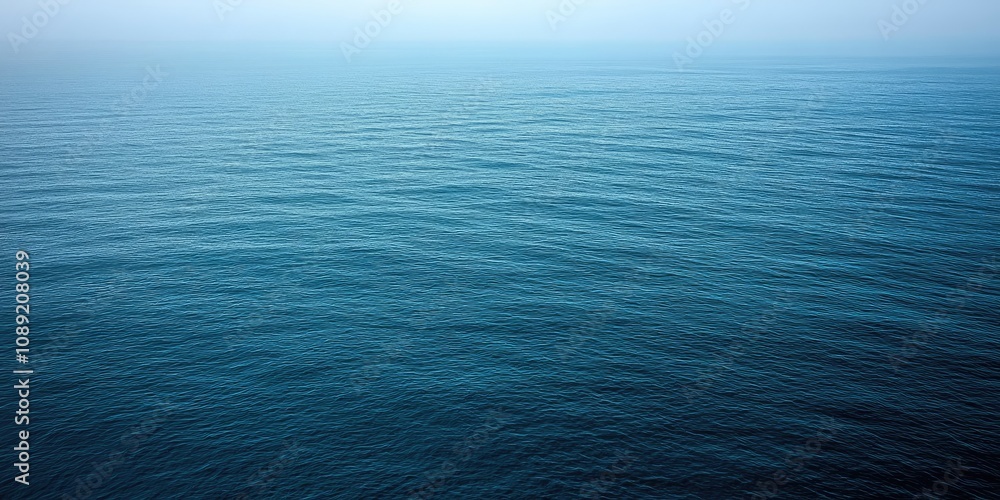 Obraz premium Under a muted winter sky, endless waves ebb and flow, reflecting various shades of blue across the water. The calmness brings a serene atmosphere for winter reflections and peace