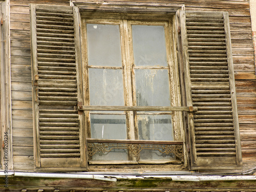 Old and derelict wooden window and wooden shutters  on a medieval house in the center of a nothen french city photo