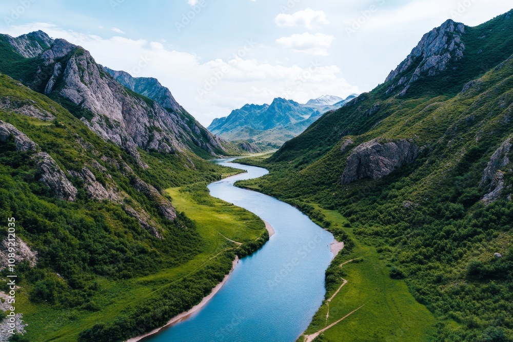 A scenic aerial view of a winding river surrounded by lush green hills and majestic mountains under a clear blue sky. A scenic aerial view of a winding river surrounded by lush green hills and majestic mountains under a clear blue sky.