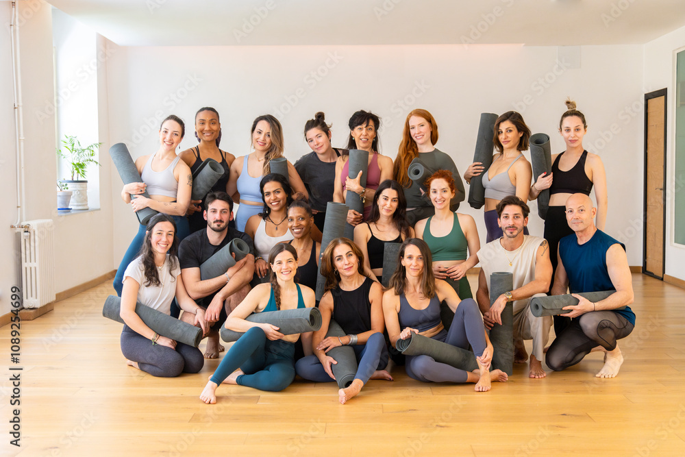 Yoga teachers posing with mats in studio after training course Yoga teachers posing with mats in studio after training course