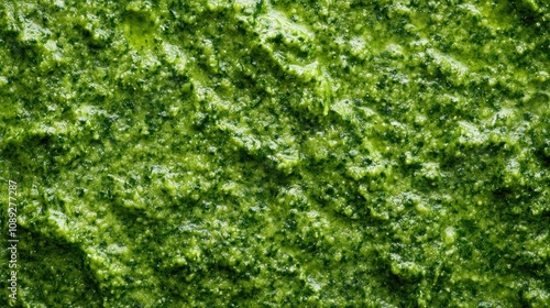Vibrant green basil pesto showcasing a rich, creamy texture with flecks of fresh herbs, perfect for culinary presentations and appetizing dishes.