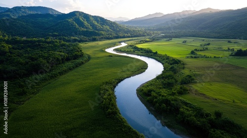 aerial view of a winding river through lush green fields and mountains