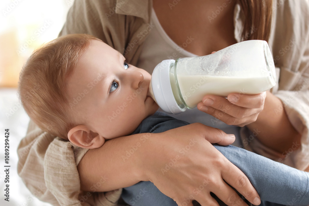 Mother feeding her little baby from bottle on bed indoors, closeup Mother feeding her little baby from bottle on bed indoors, closeup
