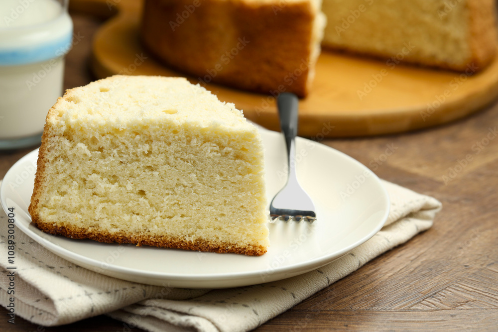 Piece of delicious sponge cake and fork on wooden table, closeup Piece of delicious sponge cake and fork on wooden table, closeup