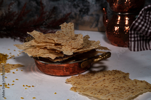 Tarhana cips, crispy snacks a traditional turkish anatolian fermented soup base made into crunchy chips made of youghurt and cereals, served with brass kitchenwear