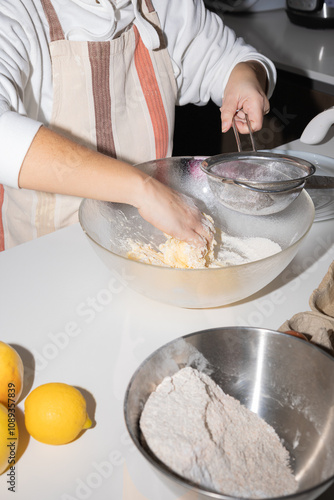 Canvas-taulu Close up hands of woman baking in kitchen sifting flour into mixing bowl with bu