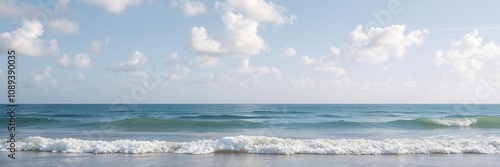 Gentle ocean waves lap against the shore as white clouds drift lazily across the sky, peaceful beach scenes, wavy shoreline, cloudy skies