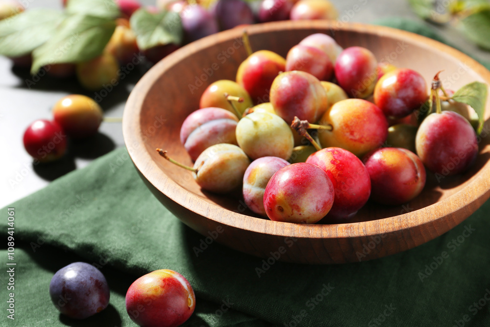 Ripe plums in bowl on grey table, closeup Ripe plums in bowl on grey table, closeup
