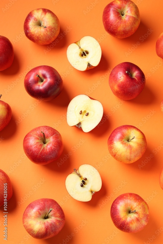Whole and cut fresh red apples on orange background, flat lay Whole and cut fresh red apples on orange background, flat lay