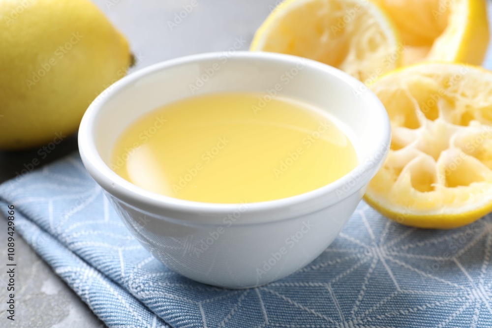 Fresh lemon juice in bowl and fruits on table, closeup Fresh lemon juice in bowl and fruits on table, closeup