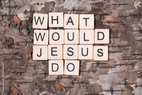 Christian religious background concept. What Would Jesus Do written with wooden block letters on natural wood bark background