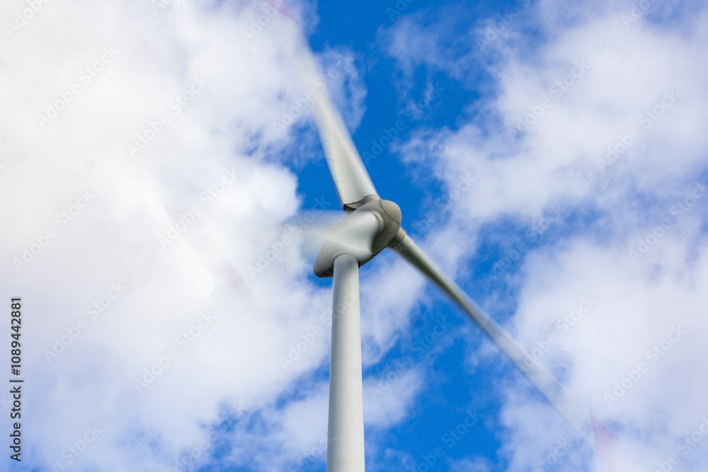 Windrad in Bewegung mit Bewegungsunschärfe vor blauem Himmel mit Wolken Windrad in Bewegung mit Bewegungsunschärfe vor blauem Himmel mit Wolken