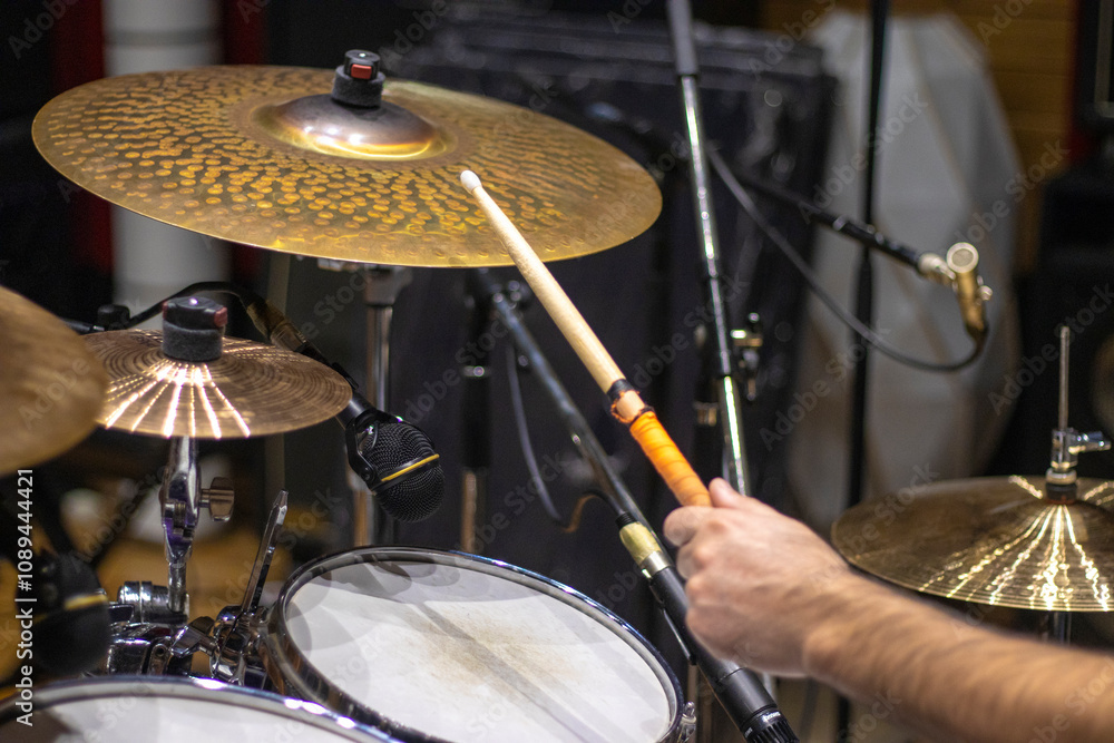 Fototapeta premium Close up of drummer hitting drum cymbal with drum stick in studio on rehearsal.