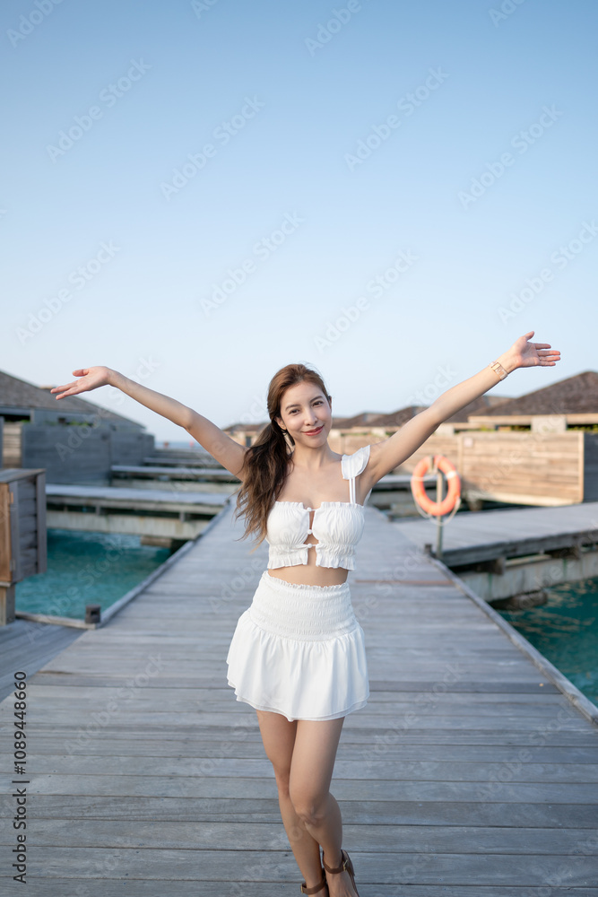 Woman walking on wooden bridge by the beach, Maldives. Woman walking on wooden bridge by the beach, Maldives.