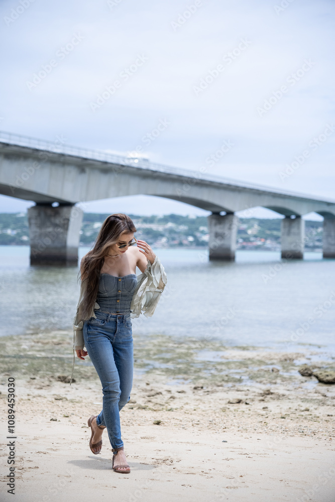 Woman relaxing on tropical beach with Kouri bridge background. Okinawa Woman relaxing on tropical beach with Kouri bridge background. Okinawa
