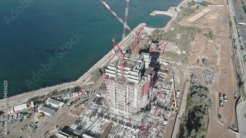 Aerial footage of skyscraper construction site with cranes in Athens, Elliniko on seaside photo