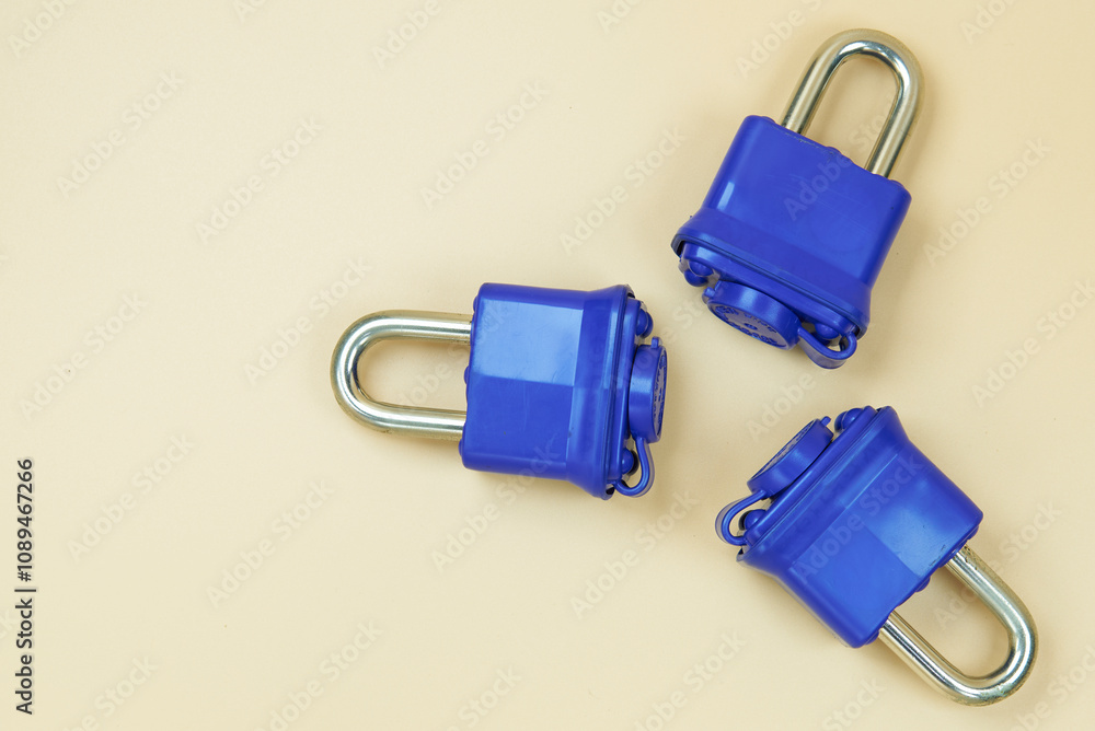 Padlock with blue plastic insulation and key, on a beige background, with free space to put text Padlock with blue plastic insulation and key, on a beige background, with free space to put text