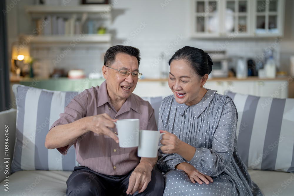 An elderly couple enjoys a peaceful moment at home, sharing smiles and drinks. The warm and cozy atmosphere emphasizes their deep connection, happiness, and the comfort of spending time together. An elderly couple enjoys a peaceful moment at home, sharing smiles and drinks. The warm and cozy atmosphere emphasizes their deep connection, happiness, and the comfort of spending time together.