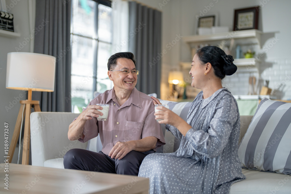 An elderly couple enjoys a peaceful moment at home, sharing smiles and drinks. The warm and cozy atmosphere emphasizes their deep connection, happiness, and the comfort of spending time together. An elderly couple enjoys a peaceful moment at home, sharing smiles and drinks. The warm and cozy atmosphere emphasizes their deep connection, happiness, and the comfort of spending time together.