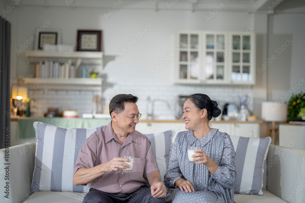 An elderly couple enjoys a peaceful moment at home, sharing smiles and drinks. The warm and cozy atmosphere emphasizes their deep connection, happiness, and the comfort of spending time together. An elderly couple enjoys a peaceful moment at home, sharing smiles and drinks. The warm and cozy atmosphere emphasizes their deep connection, happiness, and the comfort of spending time together.