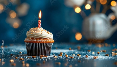 Delicious vanilla cupcake with white frosting, sprinkled with golden sugar and topped with a lit candle, on a bright black background, perfect for a birthday or holiday.