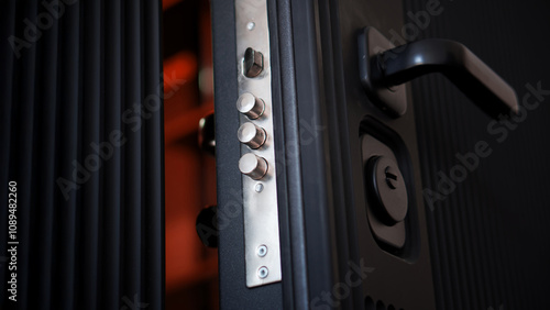 Extended door lock bolts on an open black armored entrance door. Locking mechanism on a door lock. Apartment and house protection. Photo. Selective focus