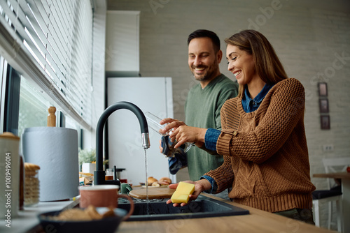 Obraz na plátně Happy couple cooperating while doing  dishes in  kitchen.