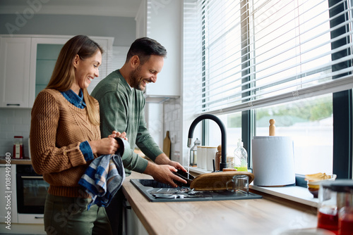 Tableau sur toile Happy couple washing dishes together in kitchen.