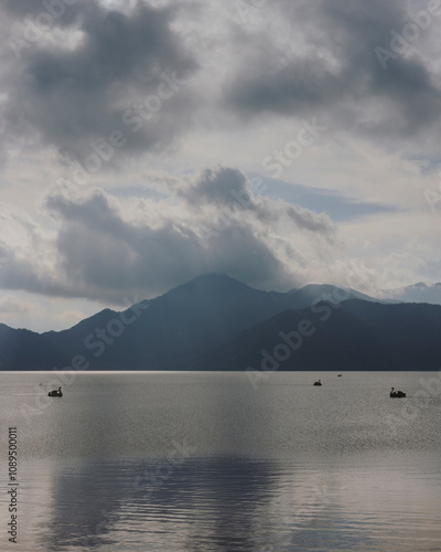 Japanese maple leaves by a lake with a swan-shaped paddle boat in Nikko, Japan.