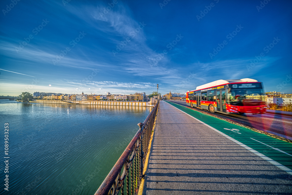 Seville, Spain, Jan 28 2021, City Bus Crossing Puente de Triana in Seville at Sunset Seville, Spain, Jan 28 2021, City Bus Crossing Puente de Triana in Seville at Sunset