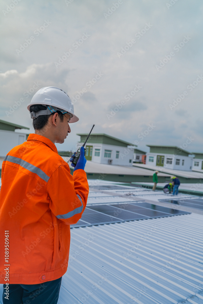 A worker in an orange safety jacket inspects solar panels on a rooftop, using a laptop to ensure proper maintenance. The scene highlights renewable energy, solar technology, and sustainable practices. A worker in an orange safety jacket inspects solar panels on a rooftop, using a laptop to ensure proper maintenance. The scene highlights renewable energy, solar technology, and sustainable practices.