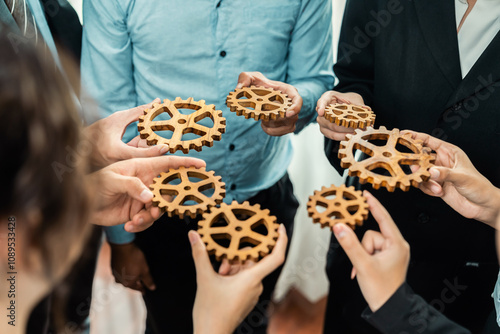 Group of multiracial business people joining gear wheels together as effective unity and productive teamwork concept. Efficient system business team process for solution solving. Meticulous