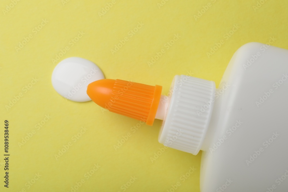 Bottle of glue on yellow background, top view Bottle of glue on yellow background, top view