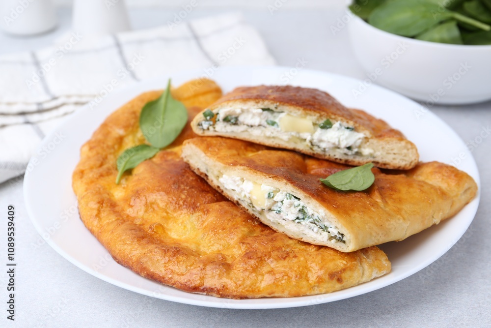 Tasty calzones with cheese and basil on light grey table, closeup Tasty calzones with cheese and basil on light grey table, closeup