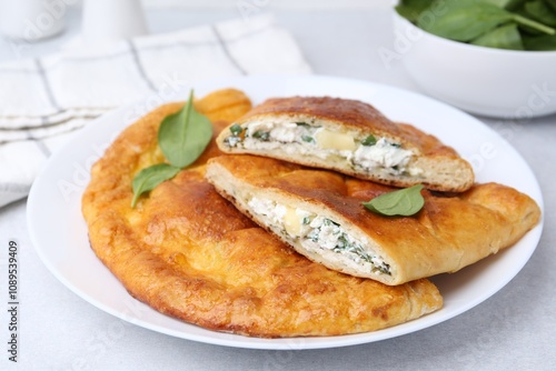 Tasty calzones with cheese and basil on light grey table, closeup