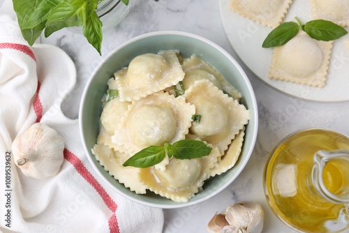 Delicious ravioli with cheese and basil served on white marble table, flat lay