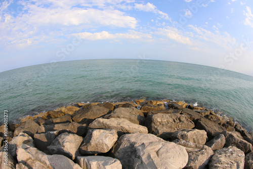 fisheye view that intentionally distorts the horizontal of the sea and the rock photo