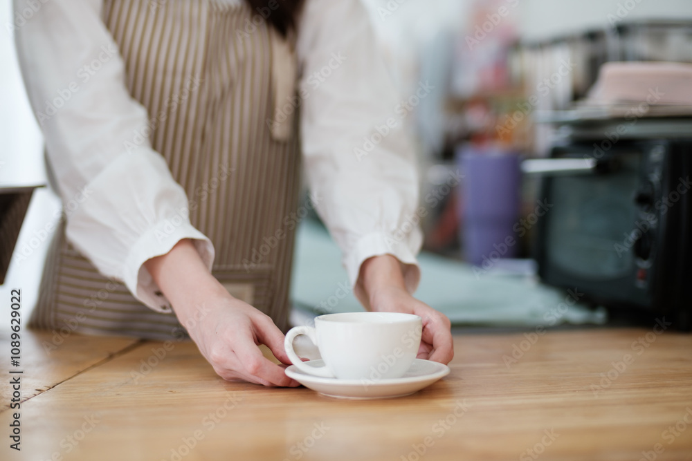 Barista placing a freshly brewed coffee cup on a wooden counter in a cozy cafe. Barista placing a freshly brewed coffee cup on a wooden counter in a cozy cafe.