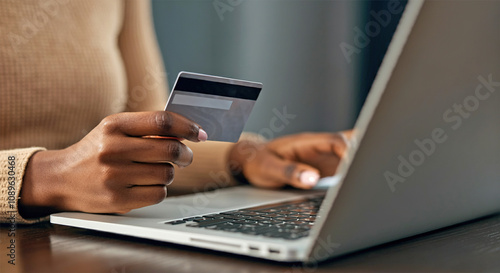 Close up of black girl hold bank credit card and type on laptop, shopping online using computer, buying goods or ordering online, entering bank accounts and details in online banking offer.