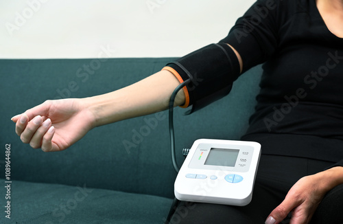 Sick young woman measuring her blood pressure at home