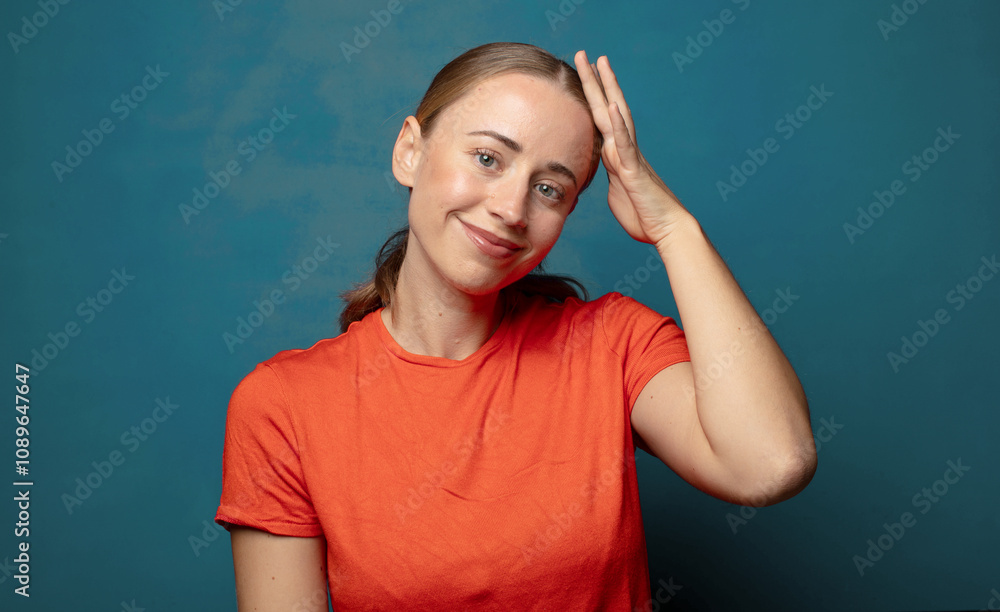 Fototapeta premium smiling cheerfully and casually, taking hand to head with a positive, happy and confident look