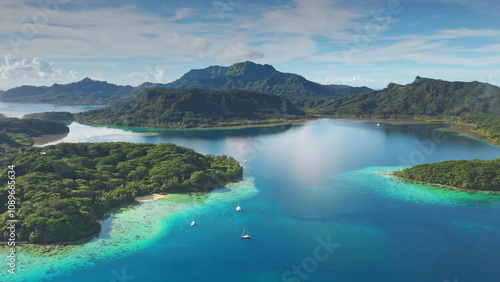 Turquoise water lagoon and green islands with sailboats yachts anchoring near motu in French Polynesia. Remote wild nature tropical paradise, exotic summer luxury travel. Drone aerial panorama shot photo