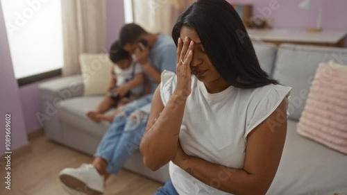 Woman feeling stressed while man sits on a couch with child in a cozy living room emphasizing family dynamics at home photo