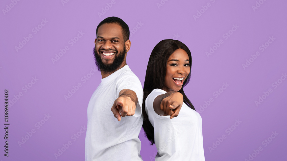 And What's About You. Portrait Of Excited African American Young Couple Pointing Fingers At Camera, Happy Man And Woman Choosing You, Standing Back To Back Isolated Over Blue Studio Background And What's About You. Portrait Of Excited African American Young Couple Pointing Fingers At Camera, Happy Man And Woman Choosing You, Standing Back To Back Isolated Over Blue Studio Background