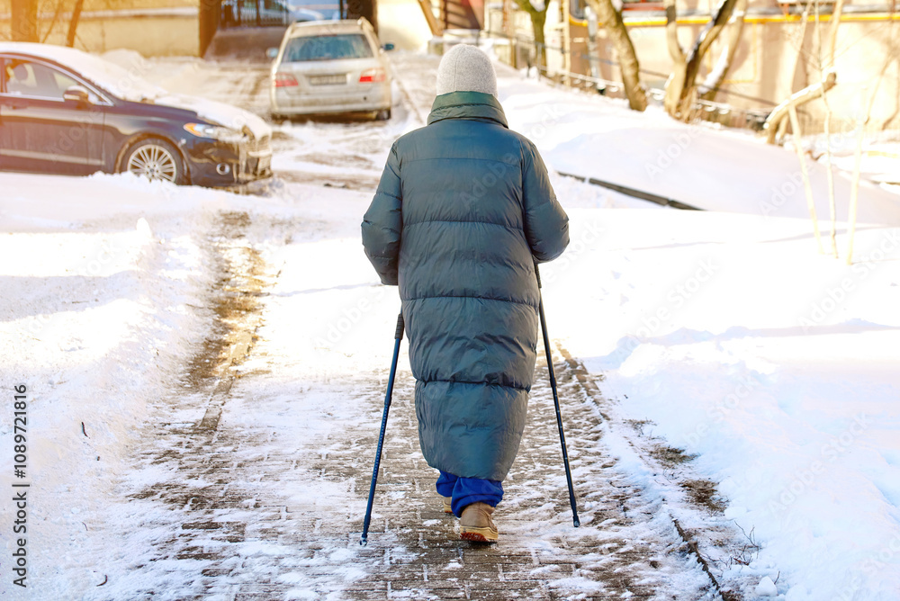 Elderly woman walking with nordic poles on frosty day, enjoying outdoor exercise and staying active during winter. Mature woman exercising with trekking poles during cold winter day