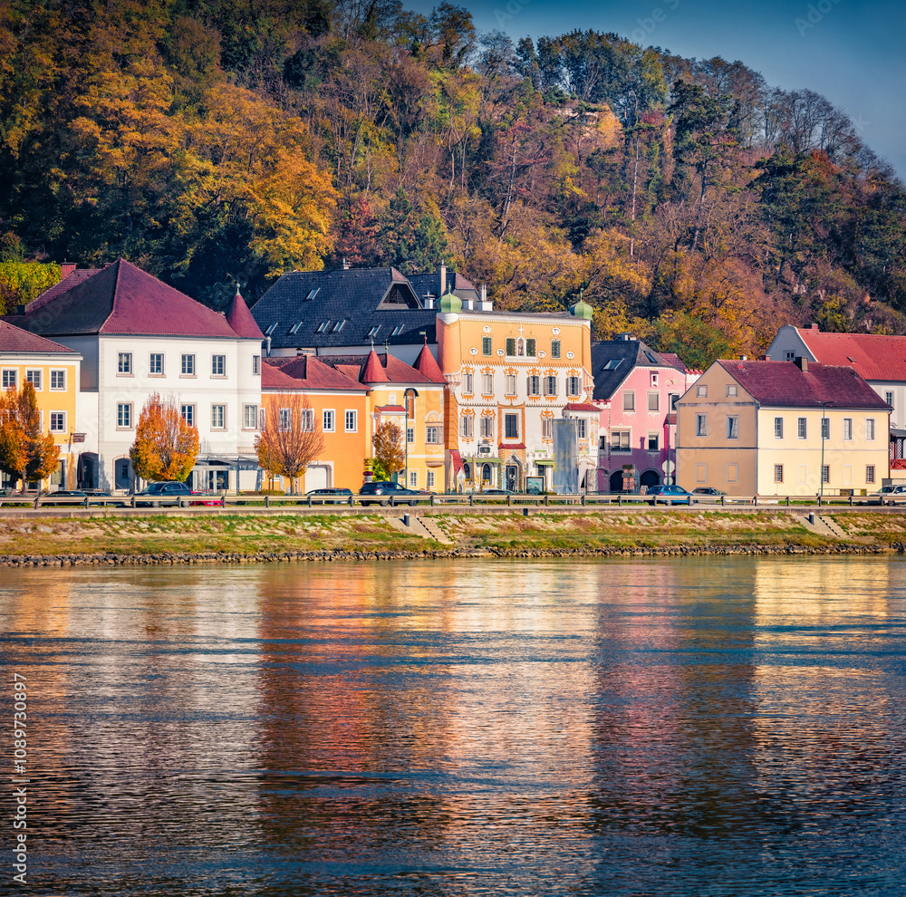 Fototapeta premium Colorful buildings on the shore of Danube river. Attractive autumn cityscape of Mauthausen market town in state of Upper Austria, Europe. Traveling concept background..