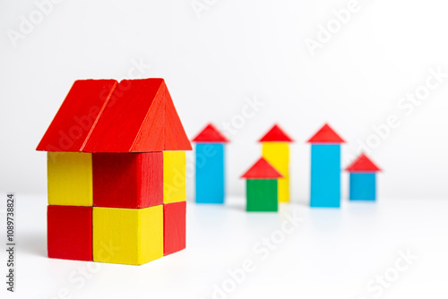 Big house on the background of small houses made of wooden multi-colored blocks on a white background
