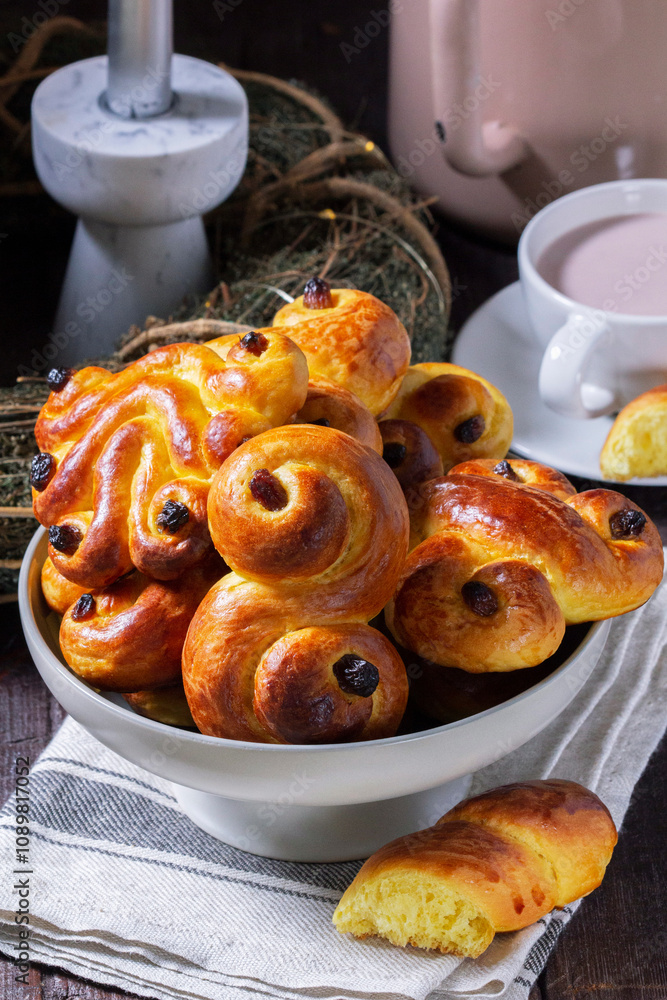 Traditional saffron Swedish buns lussekatt in different shapes, served with cocoa on a wooden table. Buns for St. Lucia's Day.